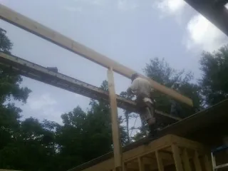 Carpenter setting a ridge beam over a new addition frame — Ice Dam Removal by Roofing Brothers in Deer Lodge