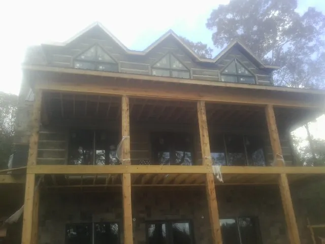 Dormers and porch framing on a large log home under construction — Roof Coating work by our crew in Deer Lodge