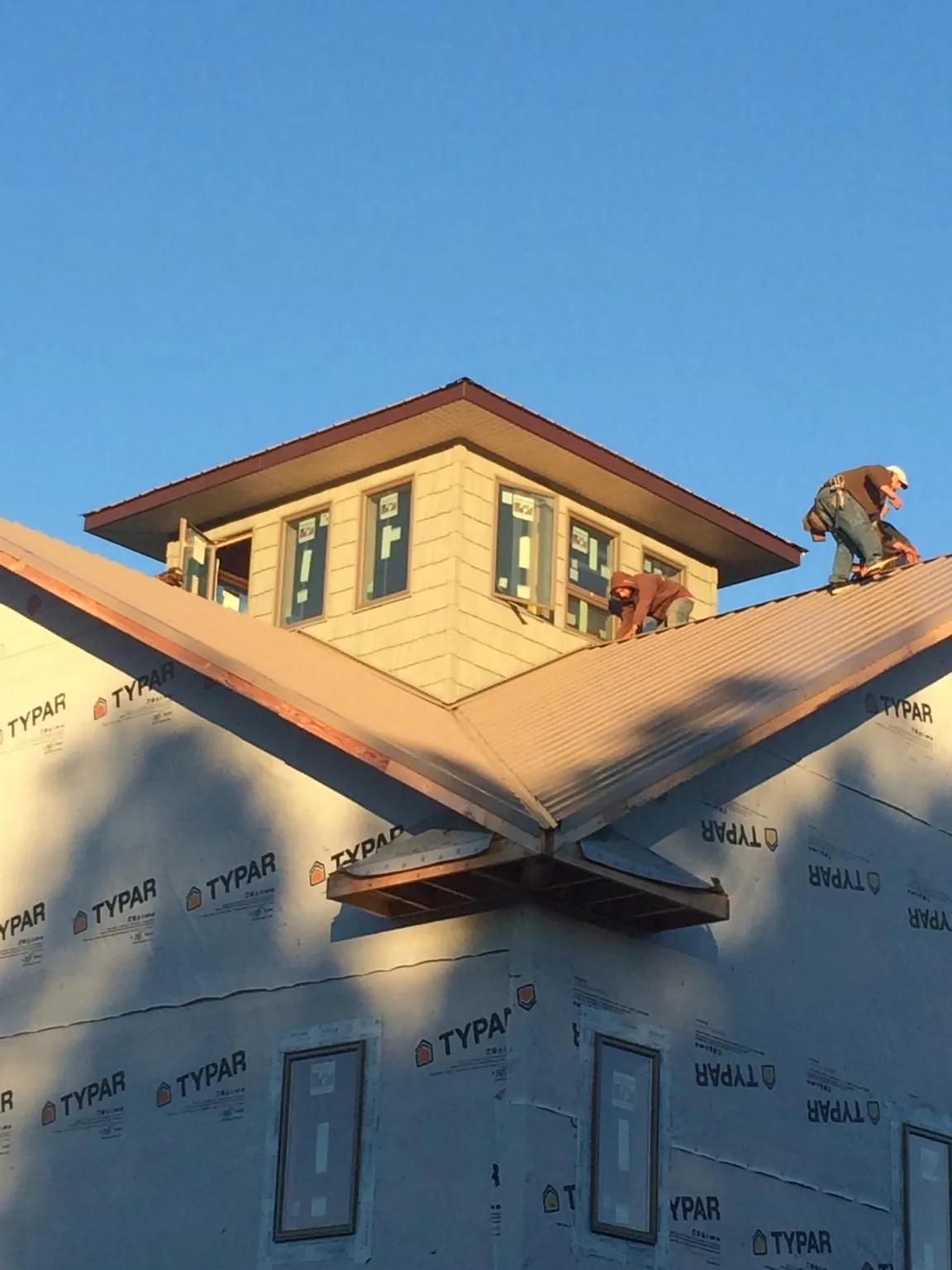 Roofers working around a rooftop cupola on a new metal roof at sunset — Roof Waterproofing in Deer Lodge by Roofing Brothers